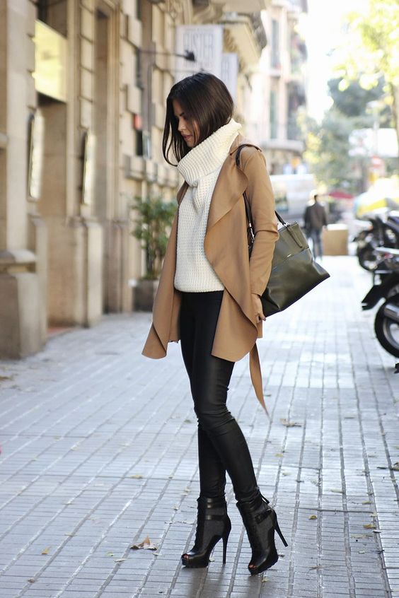 black leather pants, heeled booties, a white chunky knit sweater and a camel coat