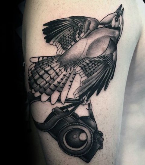 Bird and camera tattoo on the arm