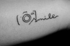Black-contour camera tattoo with word ‘smile’
