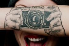 Camera and hands tattoo on the forearm