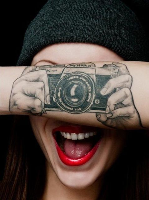 Camera and hands tattoo on the forearm
