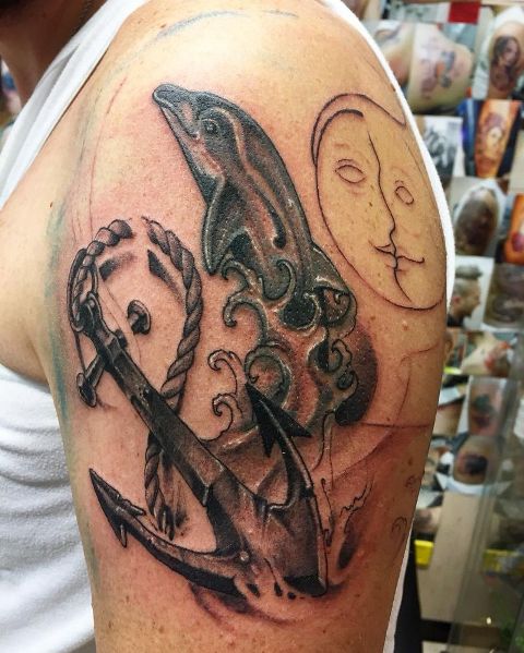 Dolphin, anchor and rope tattoo on the arm