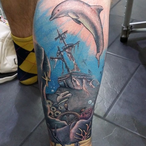 Dolphin and ship tattoo on the leg