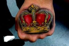 Golden and red crown tattoo on the hand