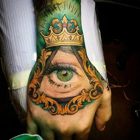 Green eye and crown tattoo on the hand
