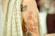 Key, bird and red flowers tattoo on the arm