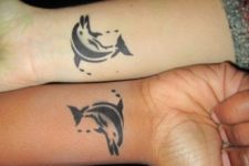 Matching dolphin tattoos on the wrists