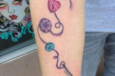 Needle and various shaped and colored buttons tattoo
