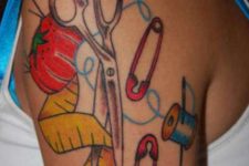 Scissors, safety pins, threads, needle tattoo on the shoulder
