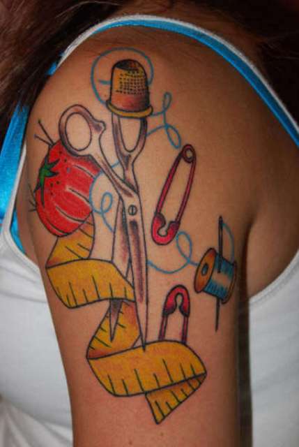 Scissors, safety pins, threads, needle tattoo on the shoulder
