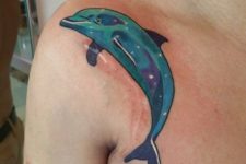 Turquoise and purple dolphin tattoo on the shoulder