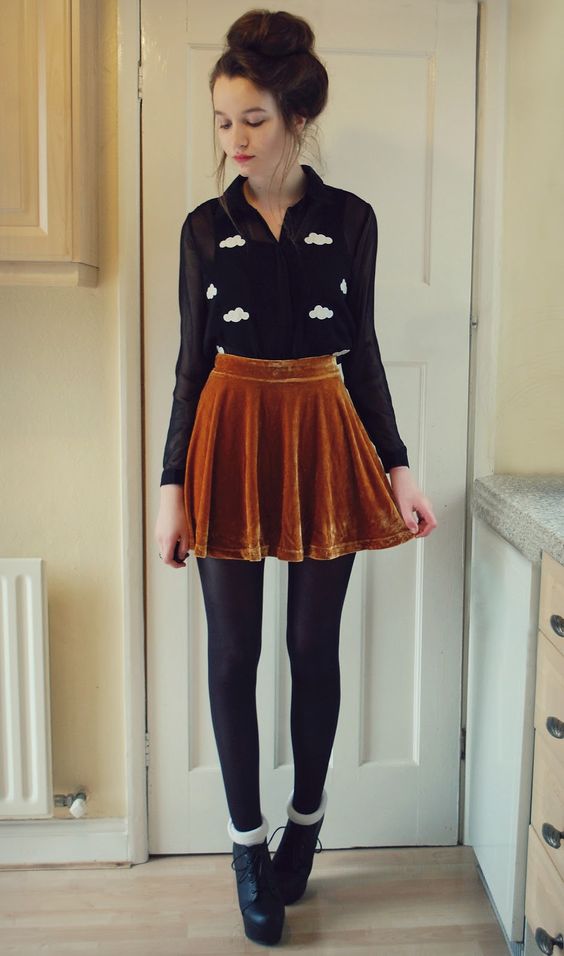 a mustard velvet mini skirt, a black sheer blouse over a top, black tights and booties
