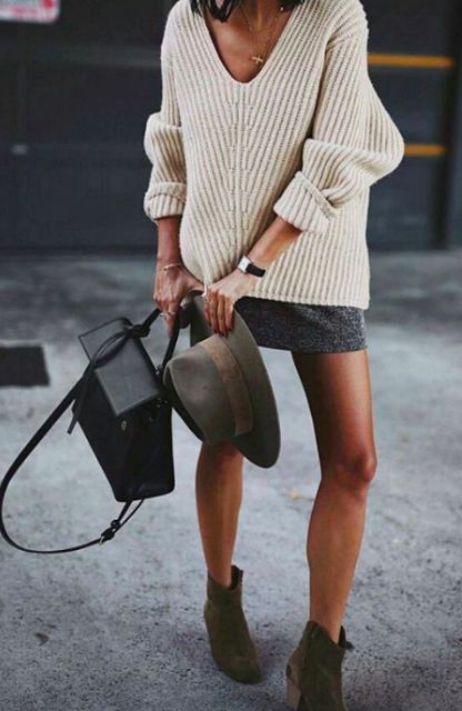 a neutral low cut sweater, a grey mini skirt, green suede boots and a black bag