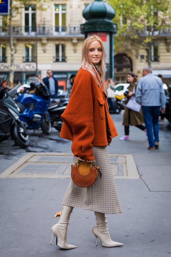 a chic slouchy cropped burnt orange coat and a matching purse, a printed midi skirt, creamy boots