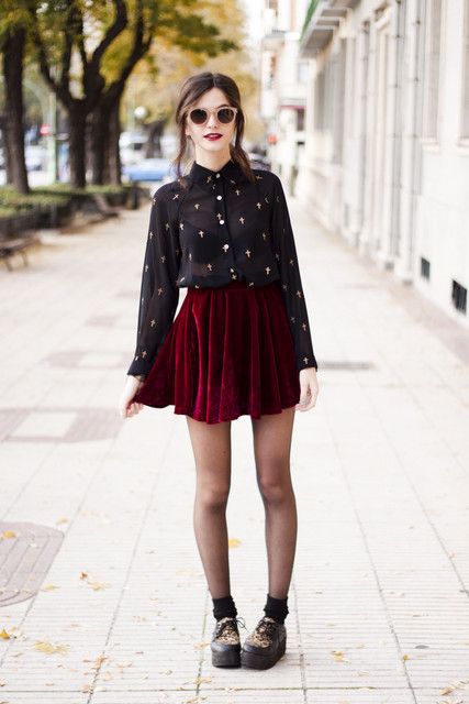 a red velvet mini pleated skirt, a black sheer shirt with a print, black tights and black boots