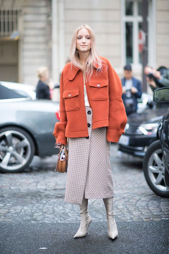 a checked wrap midi skirt with buttons, a white top, an orange short coat and creamy boots
