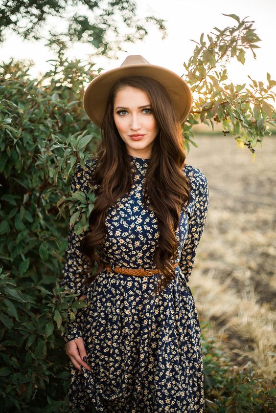 a navy floral dress, a brown leather belt, a neutral hat for a cool look