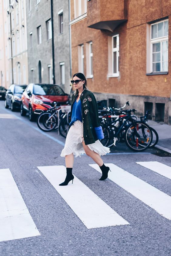 a flowy asymmetrical skirt, a blue sweater, an army jacket and black suede boots