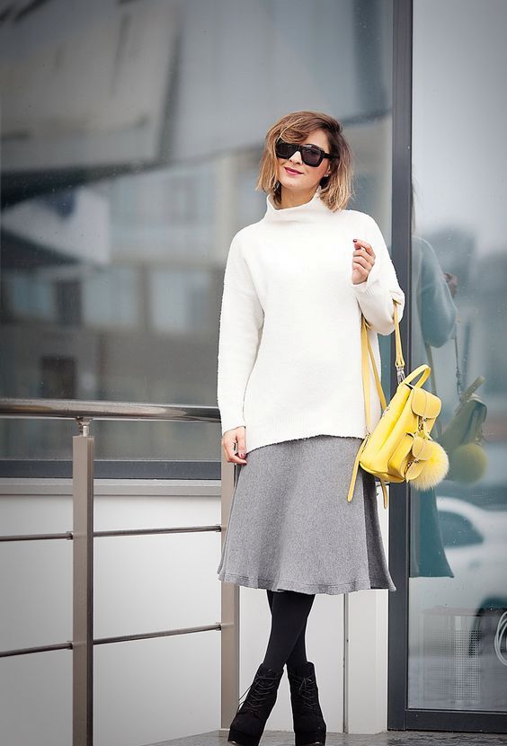 a grey midi skirt, a white turtleneck sweater, black tights, black booties and a yellow backpack
