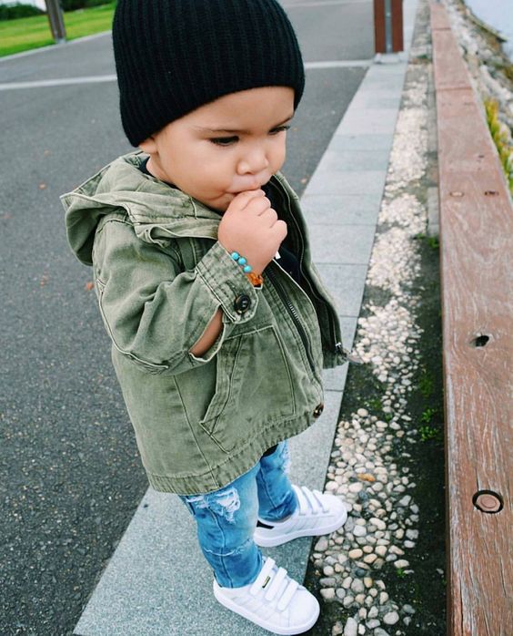 distressed blue jeans, white sneakers, an olive green denim jacket and a black beanie