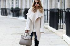 13 a sheepskin waistcoat, a white sweater, jeans and black tall boots with a grey bag