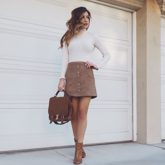 a white turtleneck, a brown mini skirt with a row of buttons, brown booties and a backpack