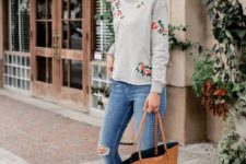 16 ripped cropped jeans, a floral sweatershirt, flat shoes and an ocher bag