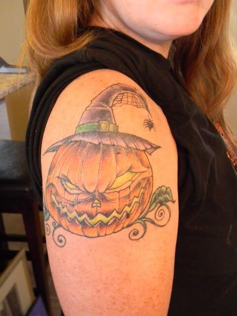 Pumpkin with evil smile, hat and spider tattoo