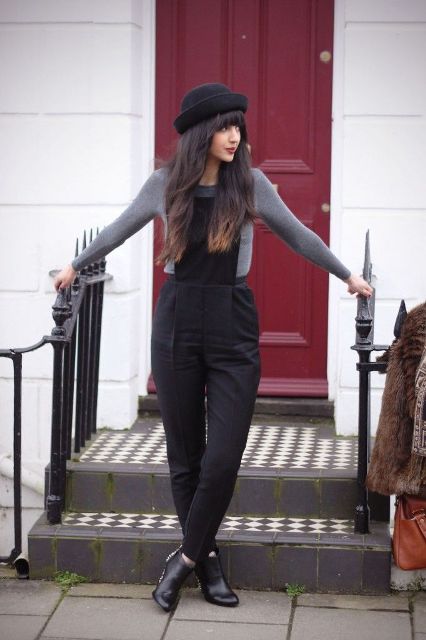 With gray shirt, black jumpsuit and ankle boots