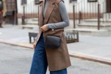 With gray turtleneck, brown long vest, boots and black bag