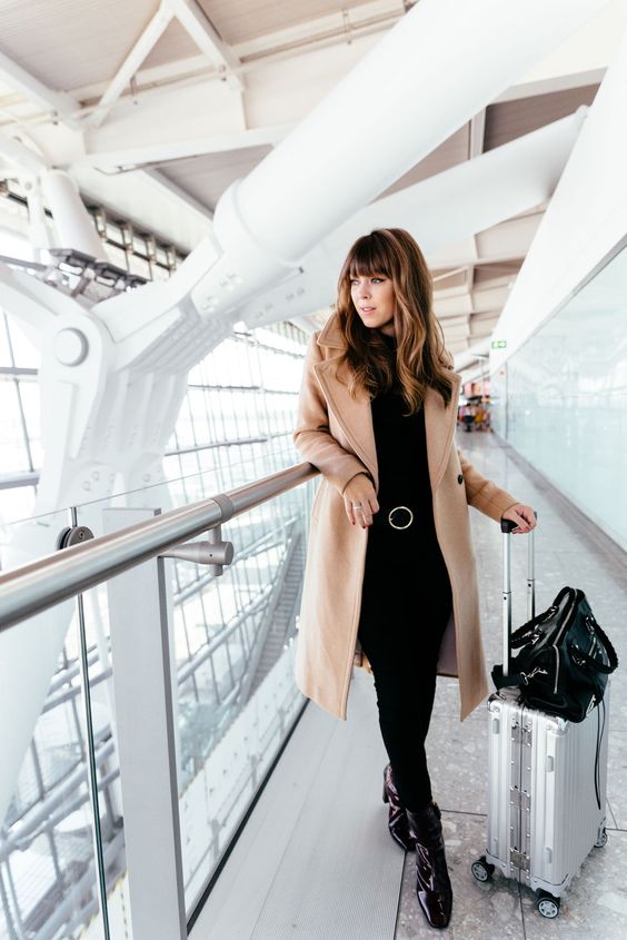 all-black look with jeans, a top, boots and a camel coat for a modern and comfy look