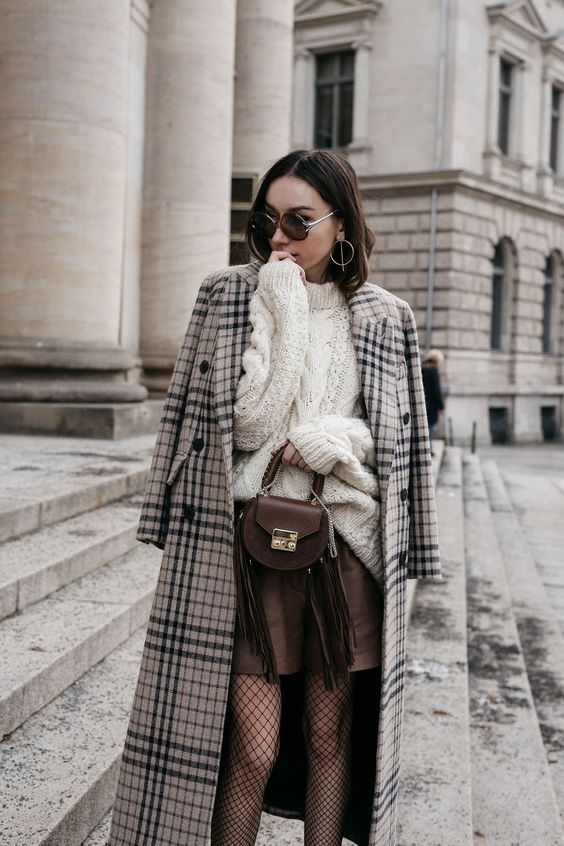 a white chunky knit sweater, a brown leather mini, tights, a plaid coat