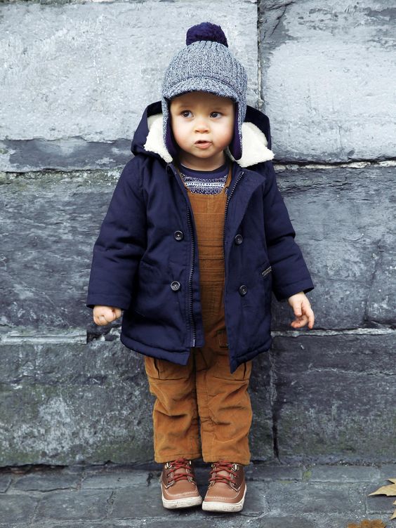 a navy boy's parka with white fur and a blue beanie