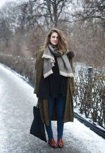 a layered look with a black sweater, a grey scarf, blue denim, an olive green coat and cognac chelsea boots