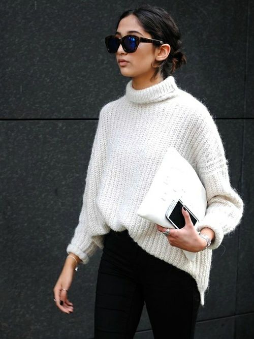 a white chunky knit sweater, black jeans and a white clutch