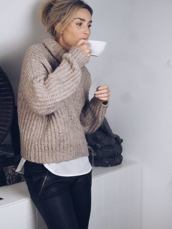 a neutral chunky knit sweater, a white shirt and black pants