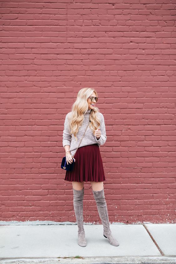 a neutral turtleneck sweater, a burgundy pleated mini skirt, grey flat suede tall boots