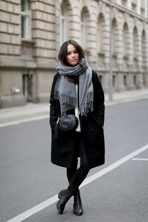 a white sweater, black denim, black boots, a black coat and a grey scarf to stay warm