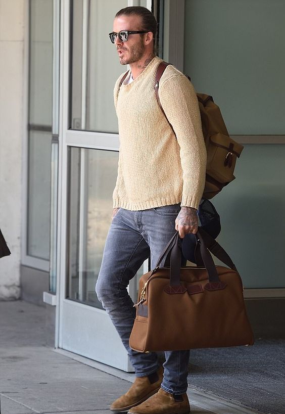 a neutral sweater over a tee, grey jeans, amber boots and a backpack