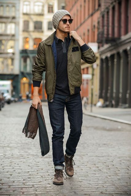 With black shirt, olive green jacket, gray beanie and brown shoes