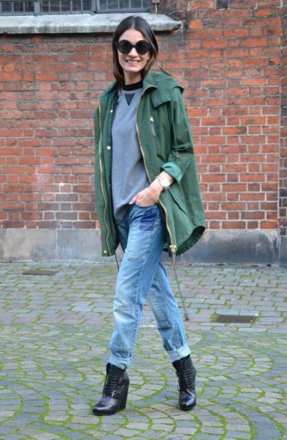 With gray sweatshirt, black boots and green parka