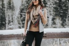 With light brown shirt, gray vest, distressed pants, duck boots and black bag