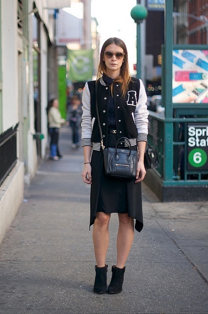 With navy blue shirt, knee-length skirt, ankle boots and bag
