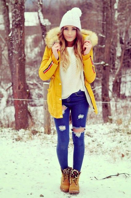 With white sweater, beanie, brown boots and distressed jeans