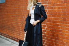 With white top, navy blue trench coat, maxi skirt and tote