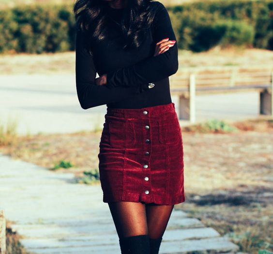 a black long sleeve top, a burgundy velvet mini skirt with a row of buttons and black suede tall boots