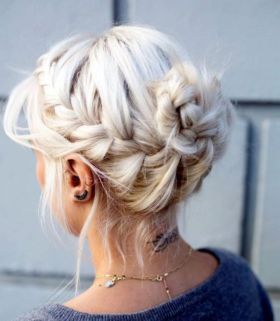 a classic messy braided updo with a bun and bangs hanging