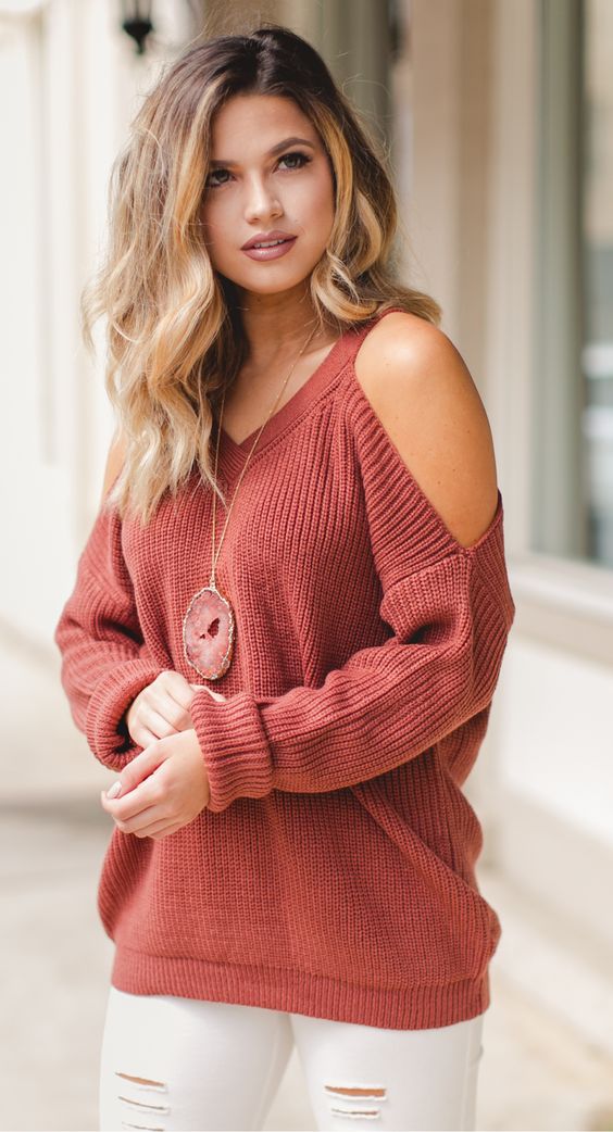white ripped jeans, a red cutout shoulder sweater and a statement necklac