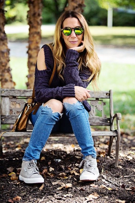 blue ripped jeans, a deep purple cable knit sweater with a cold shoulder and greey sneakers