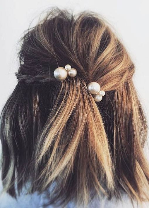 messy hair with a small braid and large pearl pins as accessories